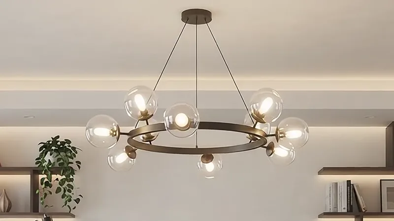 The brass pendant lit above the desk, warm light along the shelves